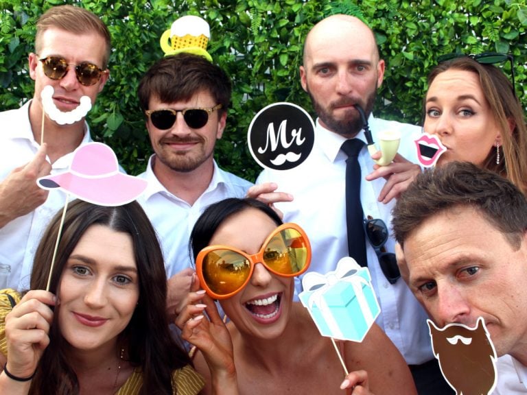 Seven wedding goers posing for photo booth shot.