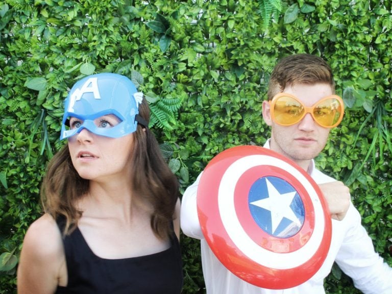 Boy and girl posing for photo booth with Captain America props