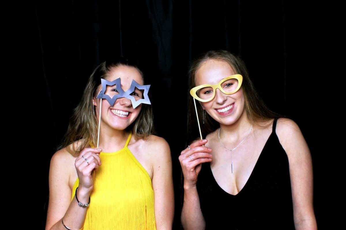 Two girls posing for photo booth with paper stick props