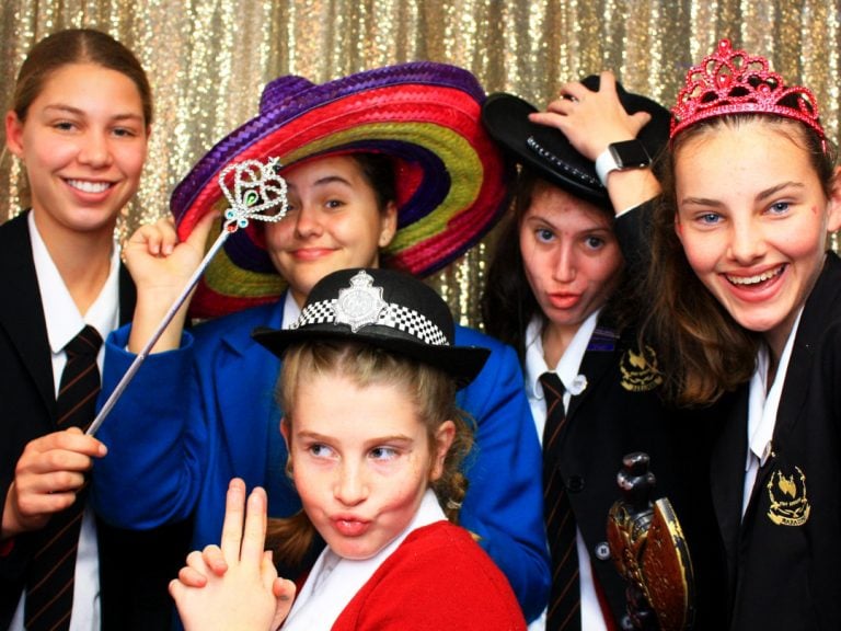 Five high school girls posing for photo booth shot with props.